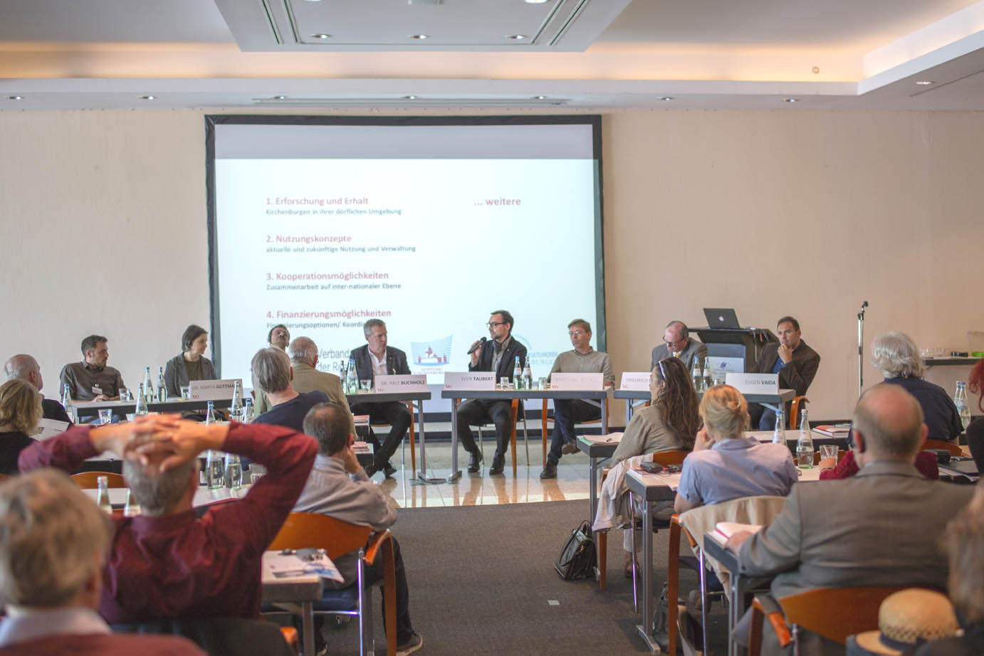 Podiumsgespräch am Ende der Konferenz: v. l. n. r. Jonas Arndt, Márta-Júlia Guttmann, Mihály Ferenc, Ralf Buchholz, Sven Taubert (Leitung), Sebastian Bethge, Friedrich Gunesch (Hauptanwalt der Evangelischen Kirche Rumäniens A. B.), Eugen Vaida. Foto: Alexander Kloos.